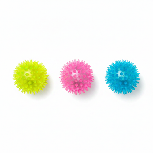 Three light-up spikey sensory balls in yellow, pink and blue laid flat on a white surface